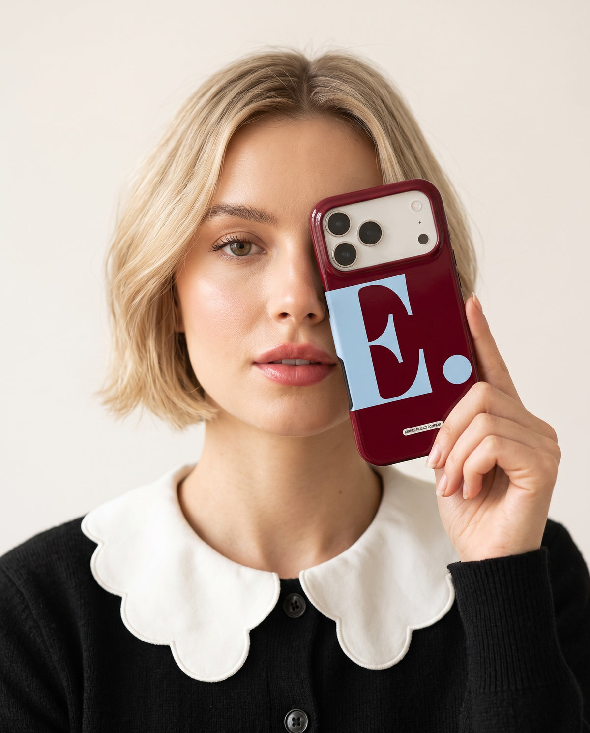 Woman holding a burgundy personalised phone case with a sky blue initial E